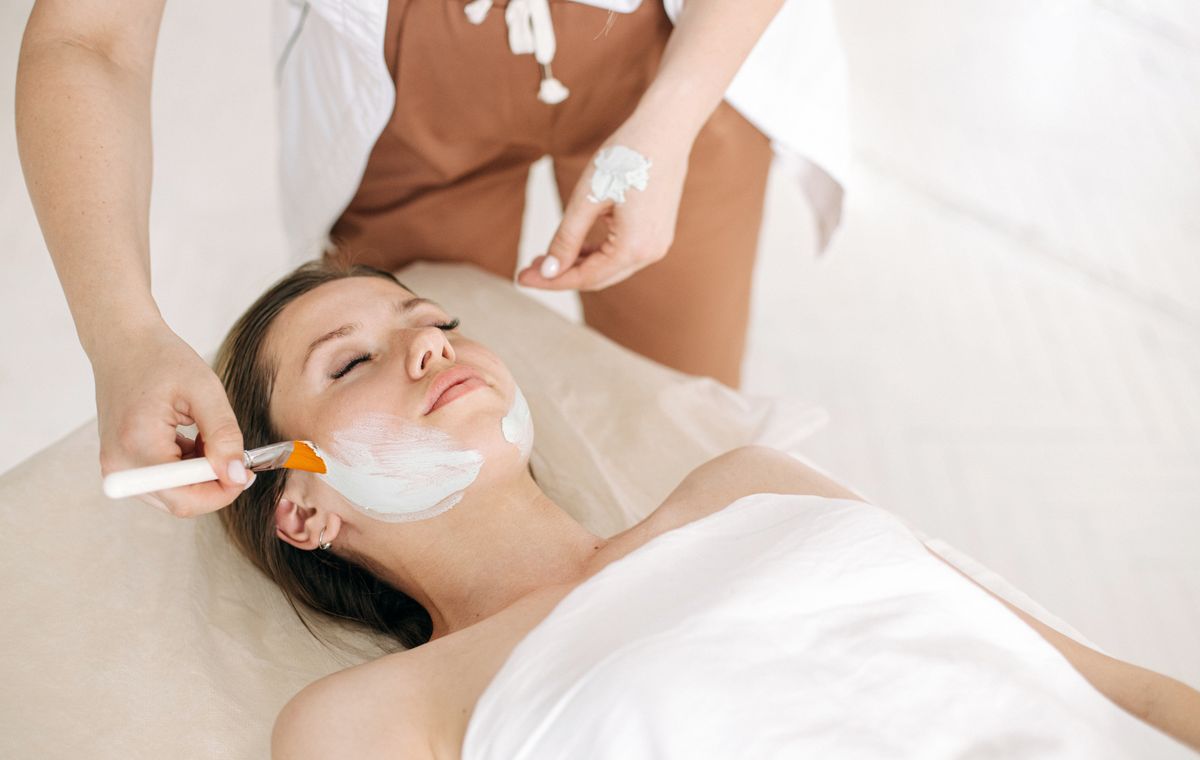 A therapist applying a skincare treatment with a brush